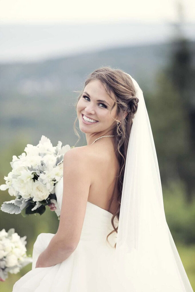 Bride holding flowers smiling at camera over her shoulder